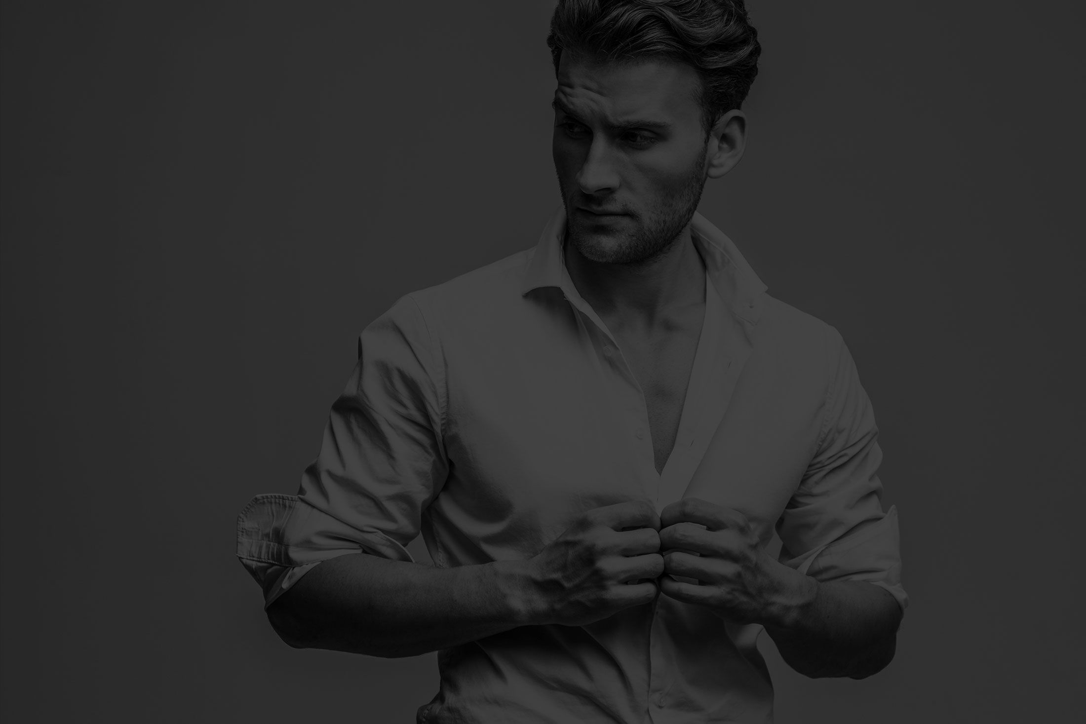 Man adjusting a shirt, looking away thoughtfully.