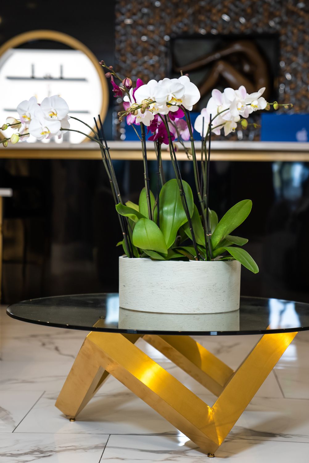 Metal sculpture of a torso against floral wallpaper.