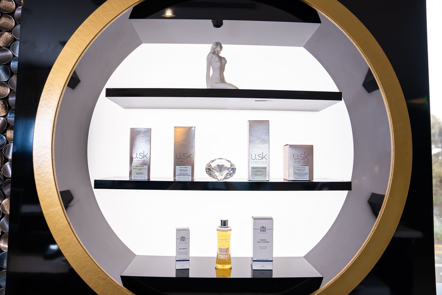 Metallic torso sculpture against floral wallpaper.