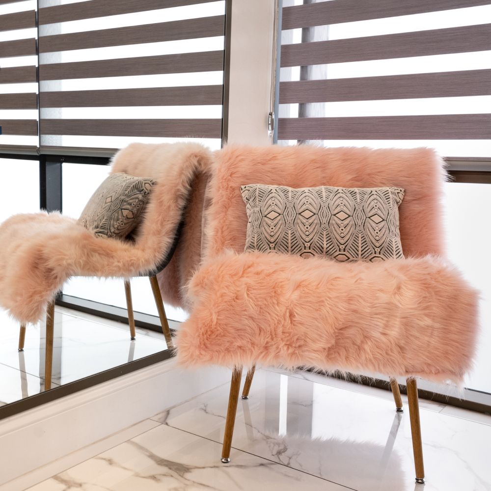 Stylish pink chair with patterned throw pillow.