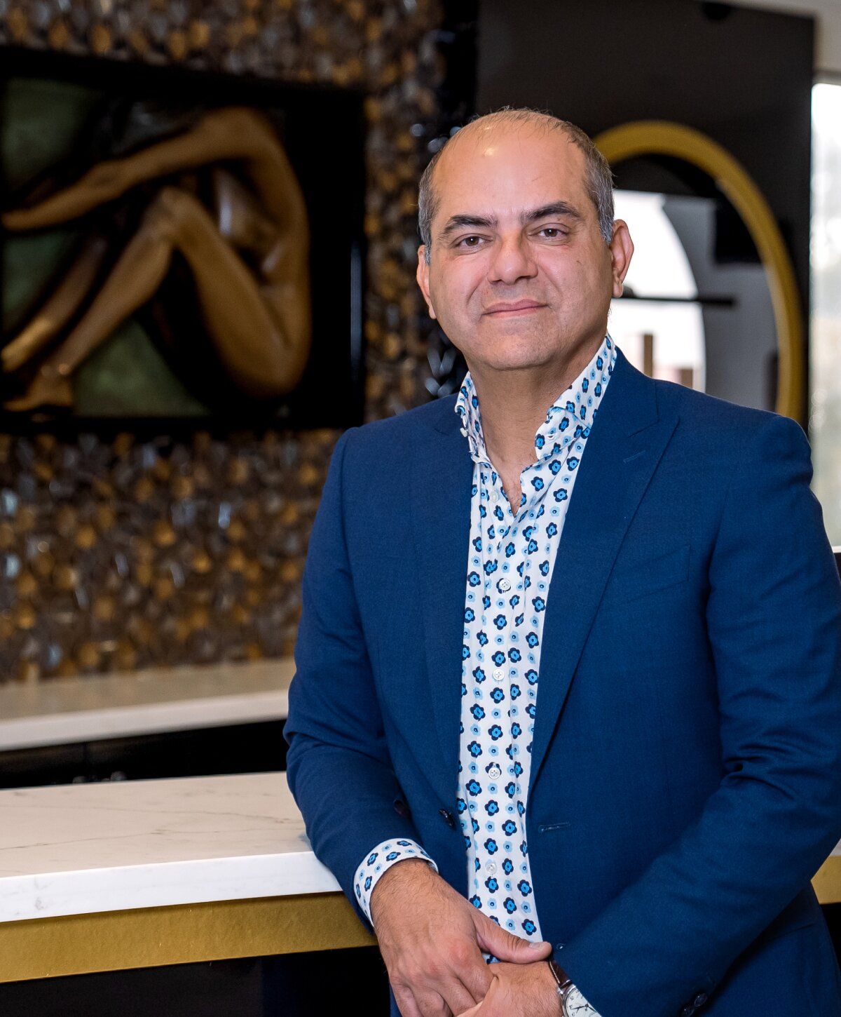 Person in a blue suit standing by a counter.