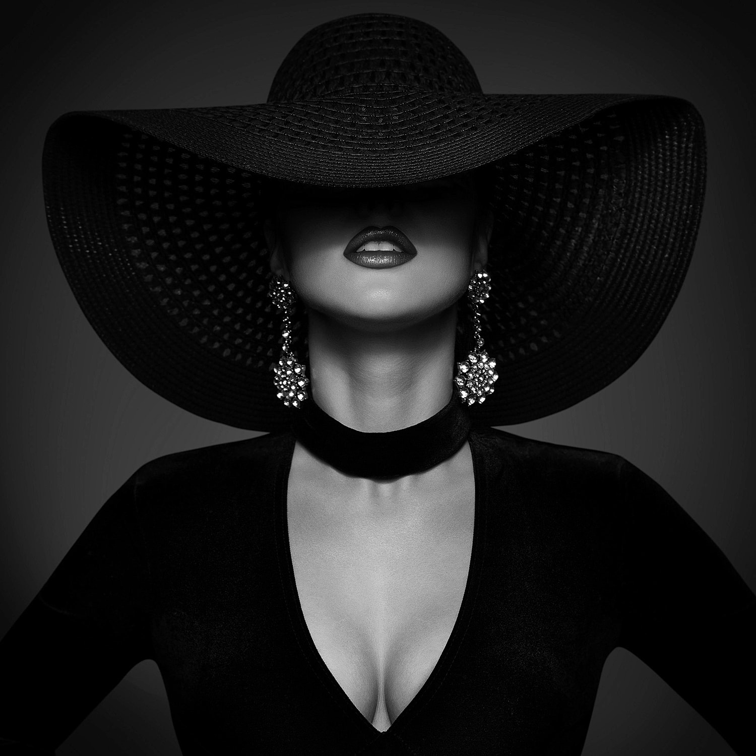Fashionable woman in dramatic black hat and earrings.