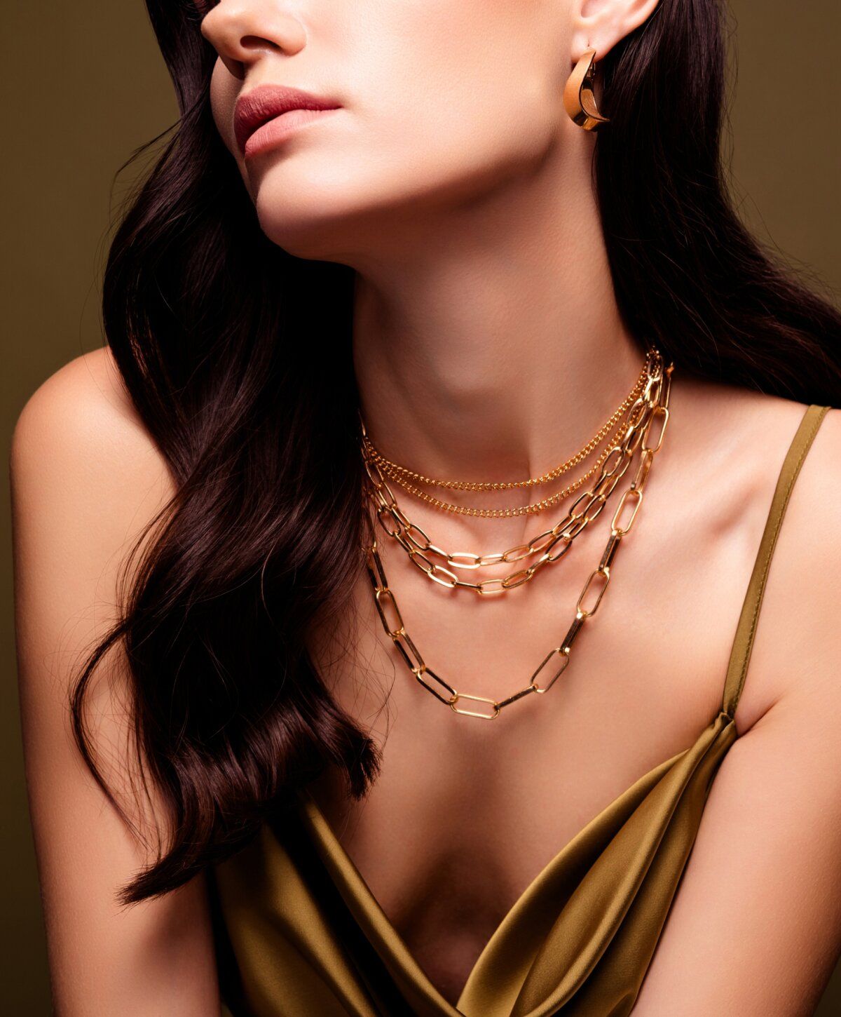 Elegant woman wearing layered gold jewelry.