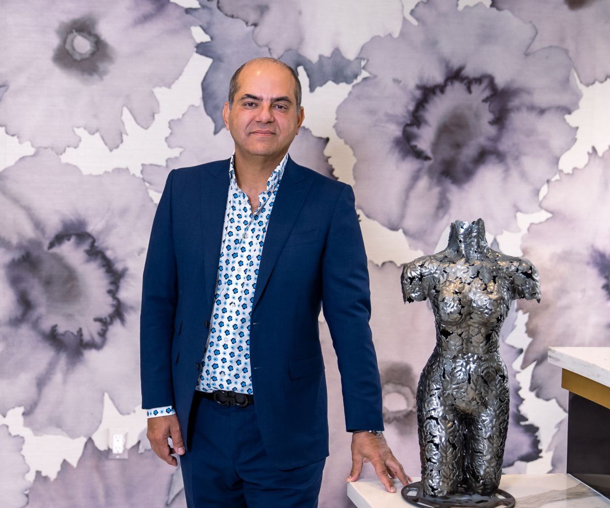 Man in blue suit next to metallic sculpture.