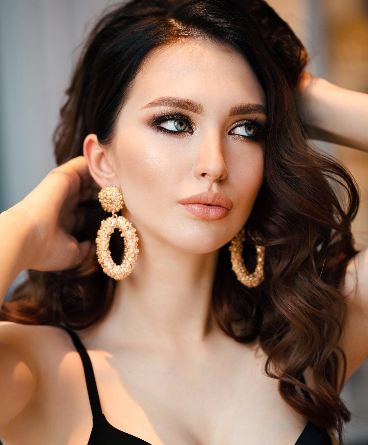 Woman with elegant earrings and soft makeup.