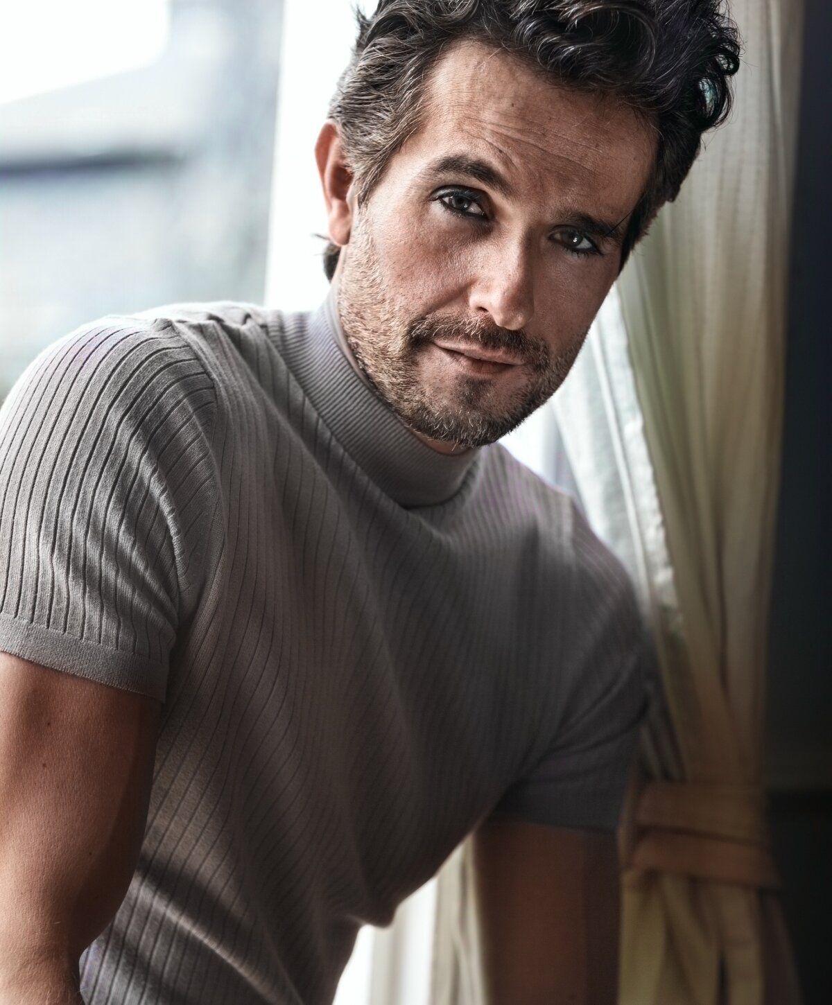 Man with tousled hair in ribbed sweater.