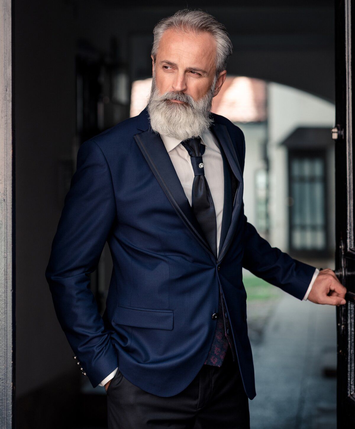Stylishly dressed older man at doorway.