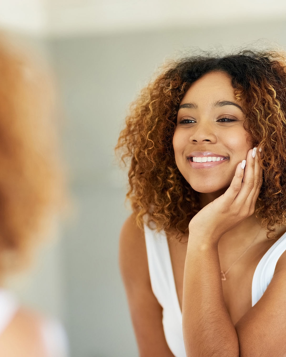 Smiling woman admiring herself in a mirror.