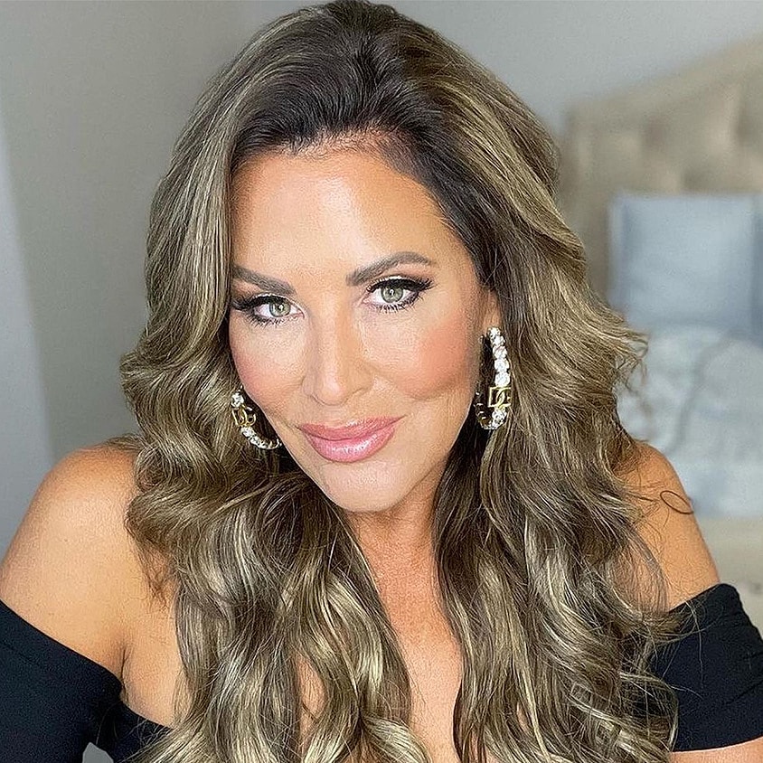 Woman with wavy hair and statement earrings.