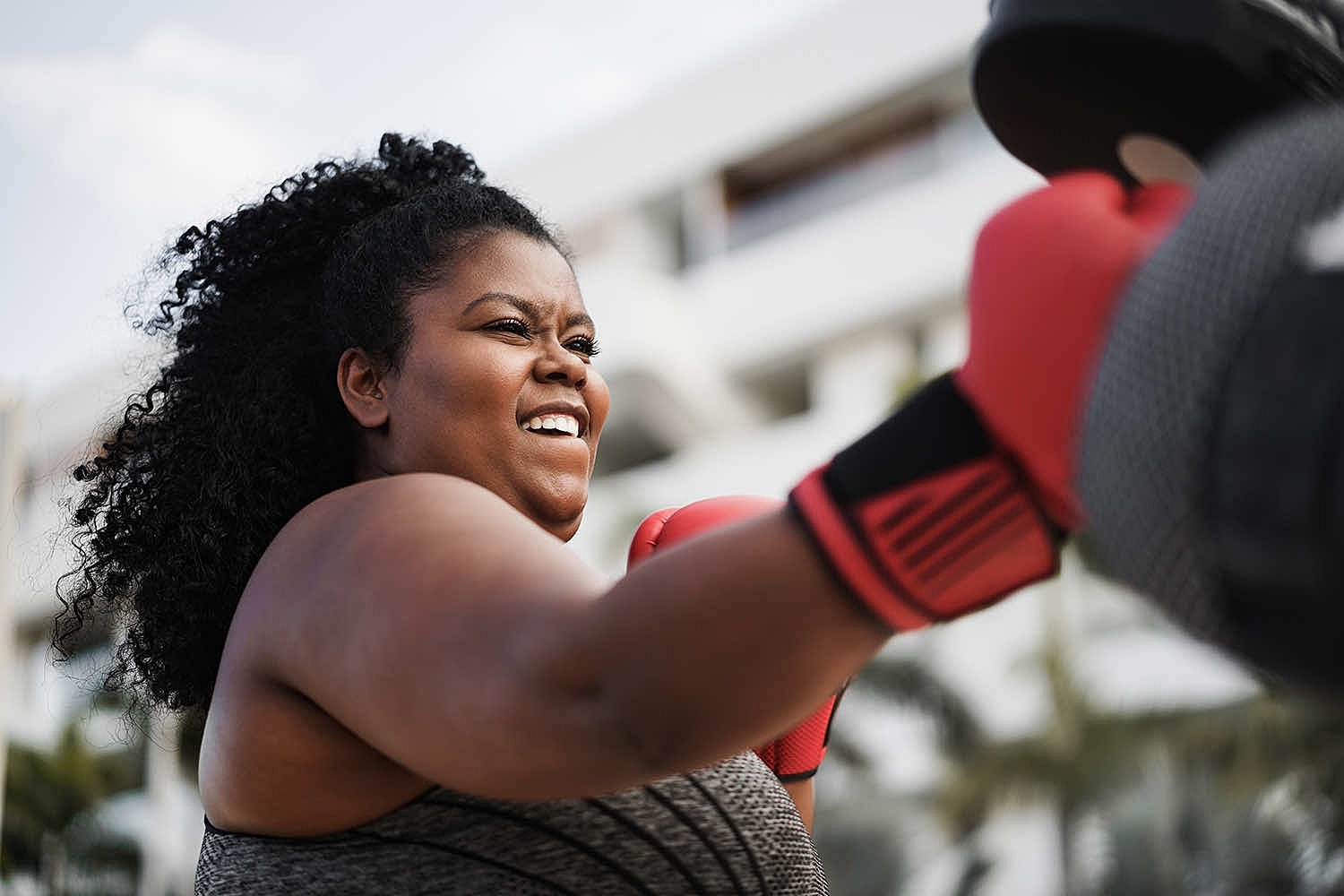 Woman training in boxing gloves outdoors.