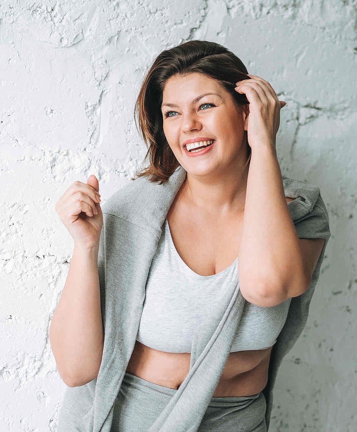 Model in beige activewear lounging on a surface.