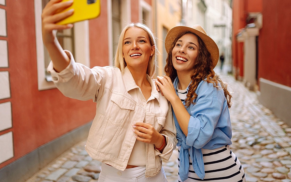Two friends taking a selfie in European alleyway.