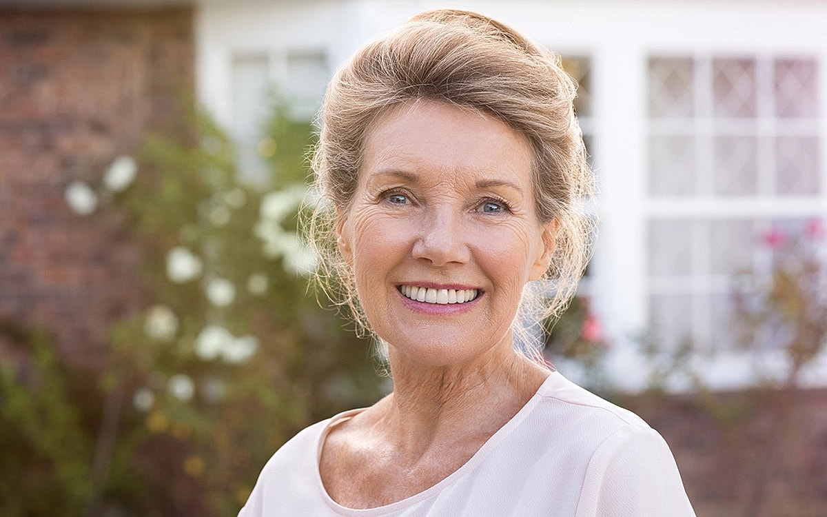 Smiling older woman in outdoor setting.