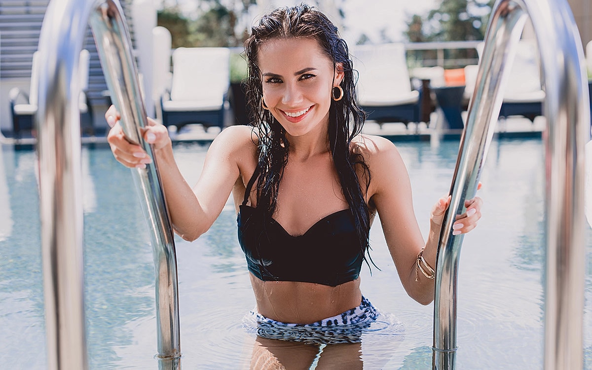 Smiling woman emerging from pool steps.