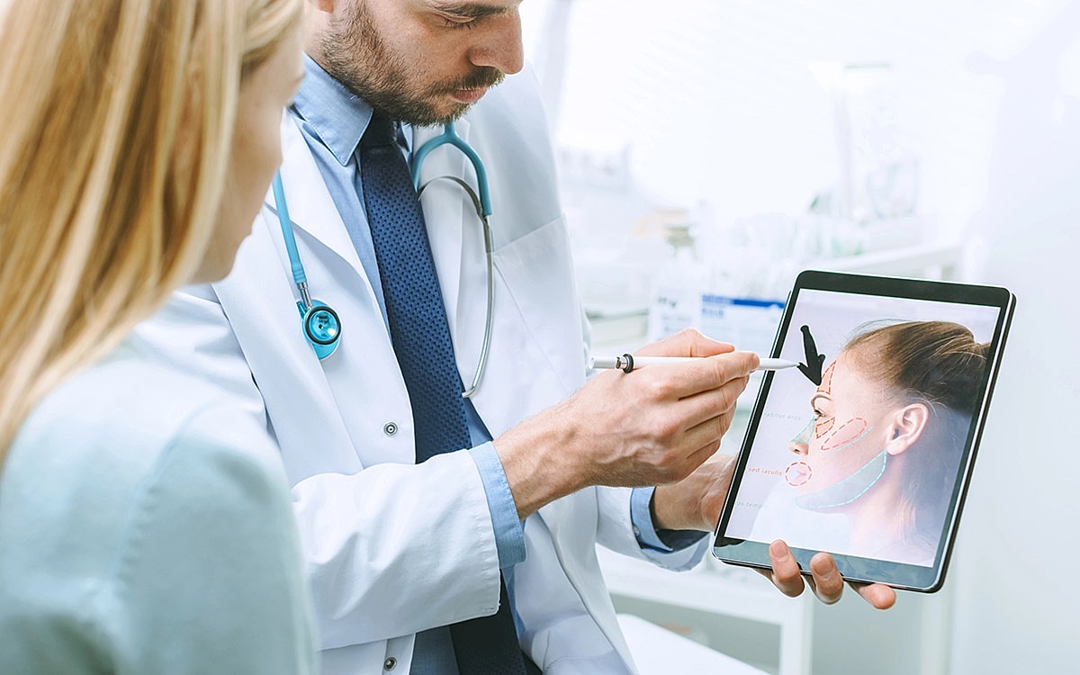 Doctor showing treatment plan on tablet to patient.