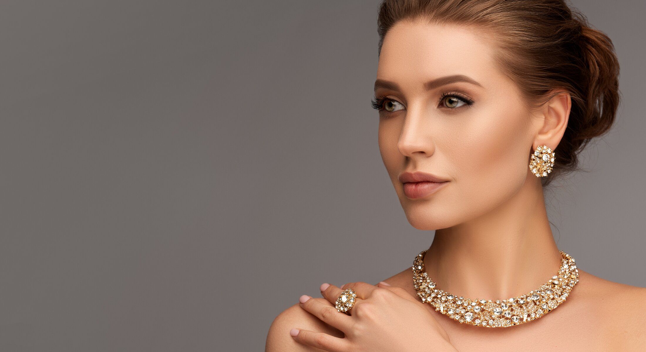 Model showcasing elegant gold jewelry and makeup.