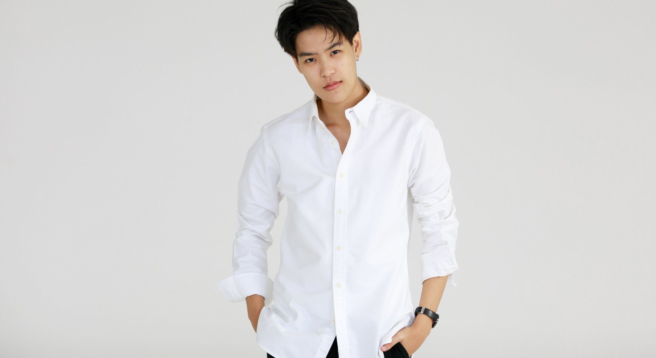 Man in white shirt posing against plain background.