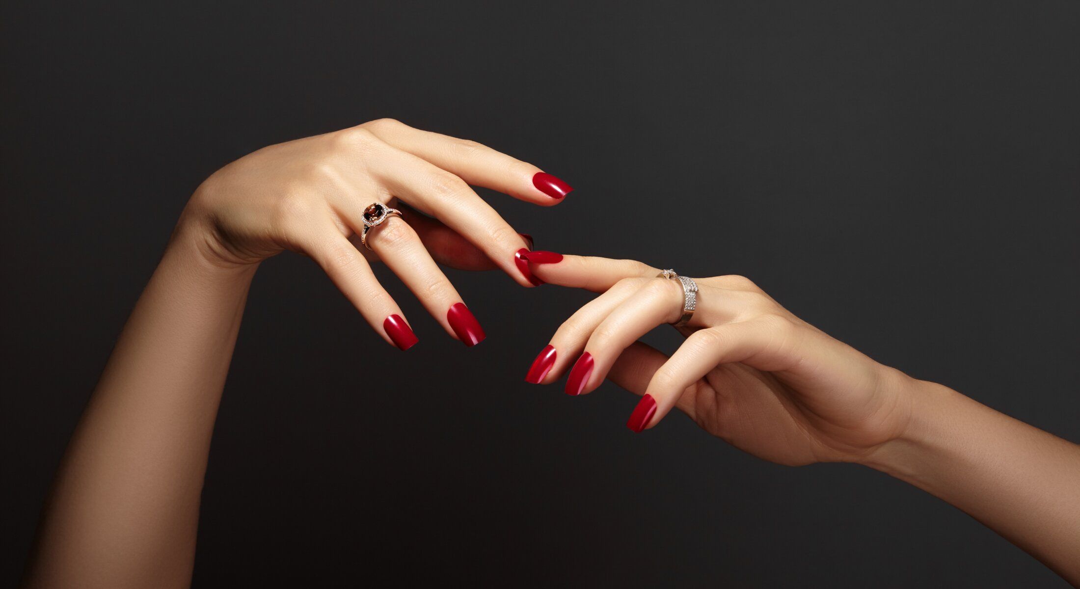 Elegant hands with red nails and rings.