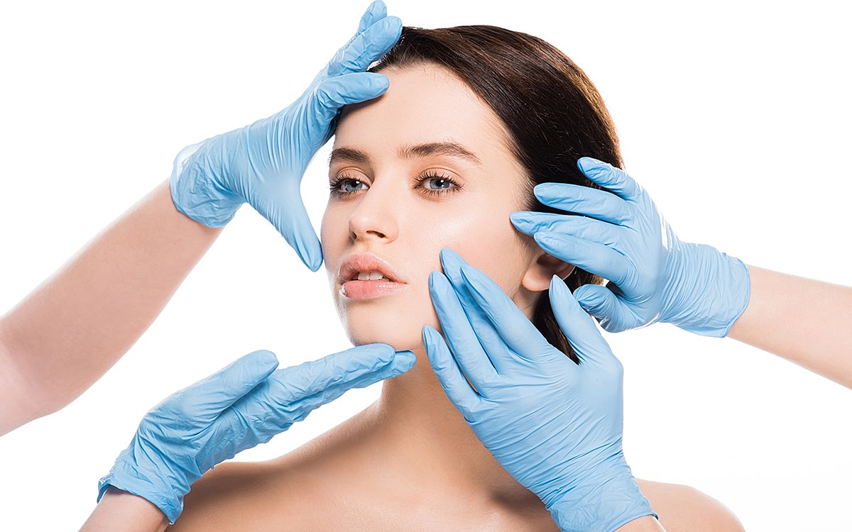 Skincare treatment with gloved hands assisting.