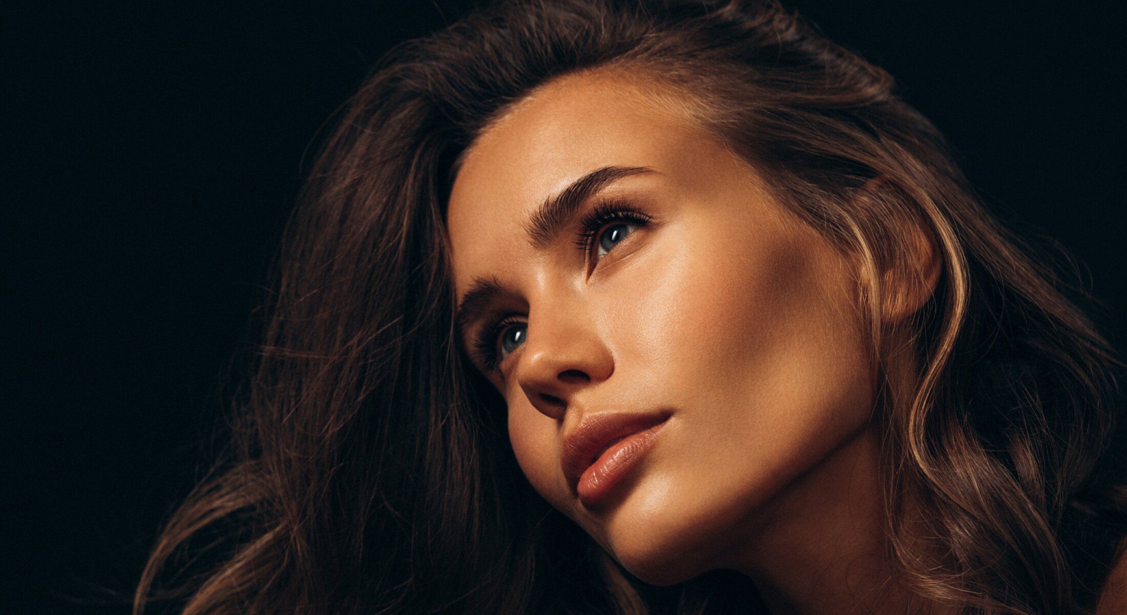 Woman with long hair against dark background.