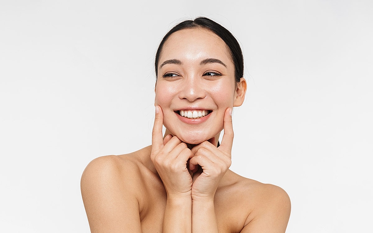 Smiling woman with glowing skin and playful expression.