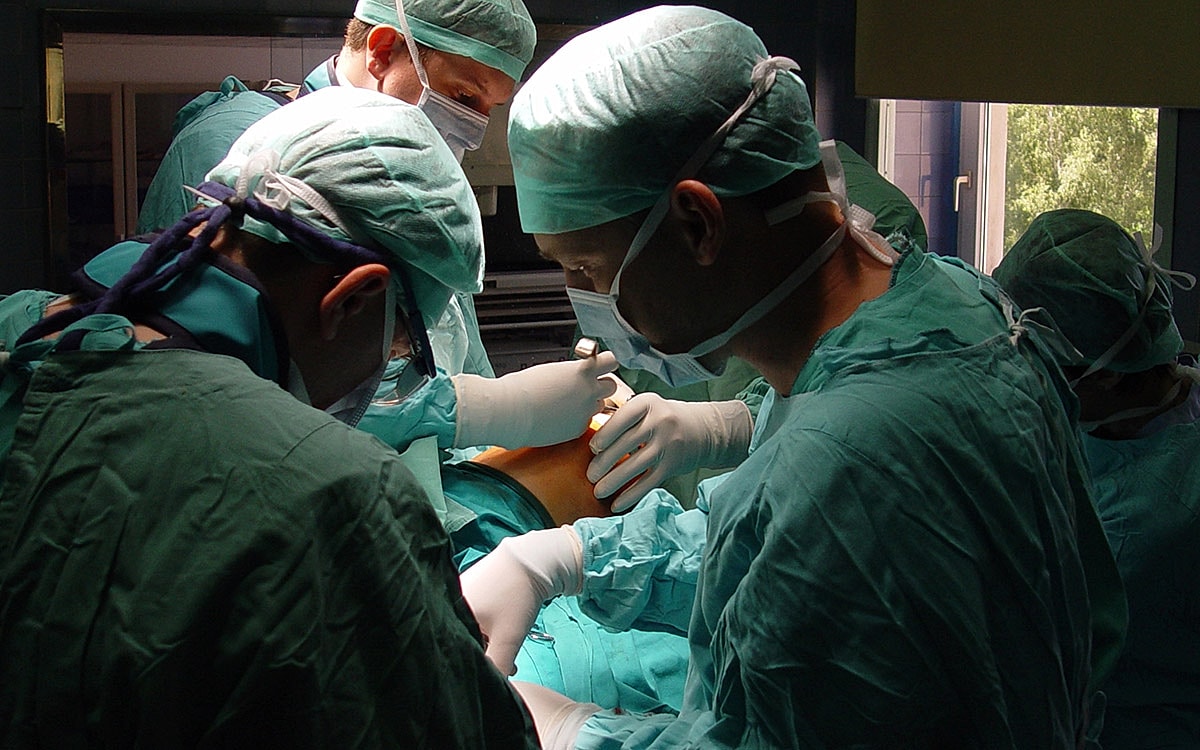 Surgical team performing an operation in scrubs.