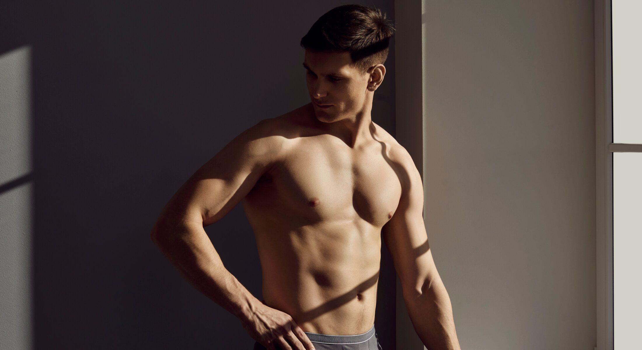 Muscular man posing in soft lighting.