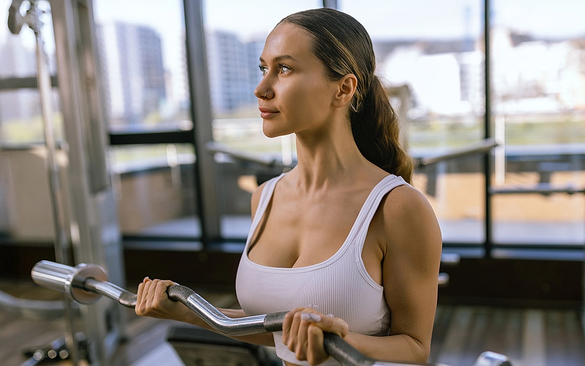 Woman lifting weights in a gym setting.
