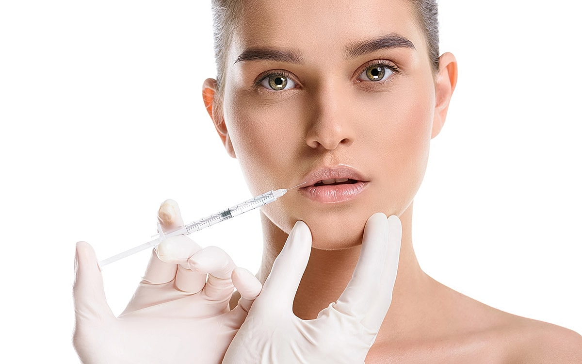 Cosmetic procedure with syringe and model's lips.