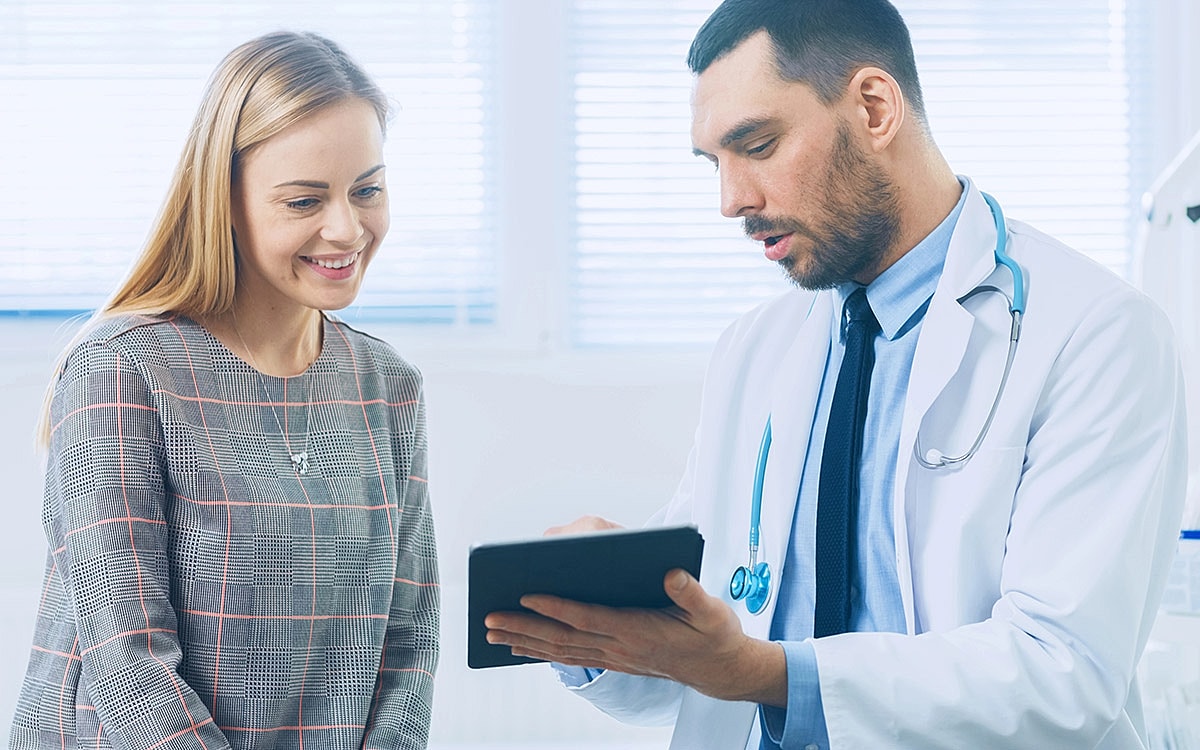 Doctor consulting with patient using tablet.