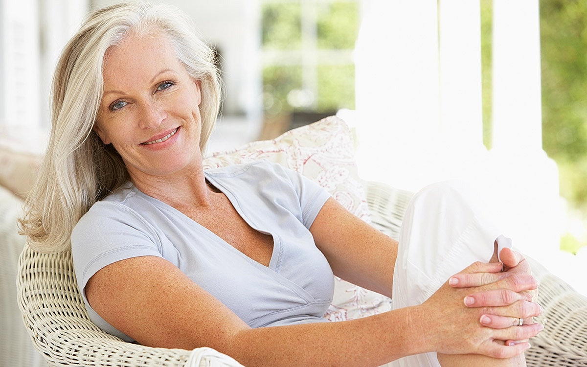 Smiling woman sitting comfortably on a porch.