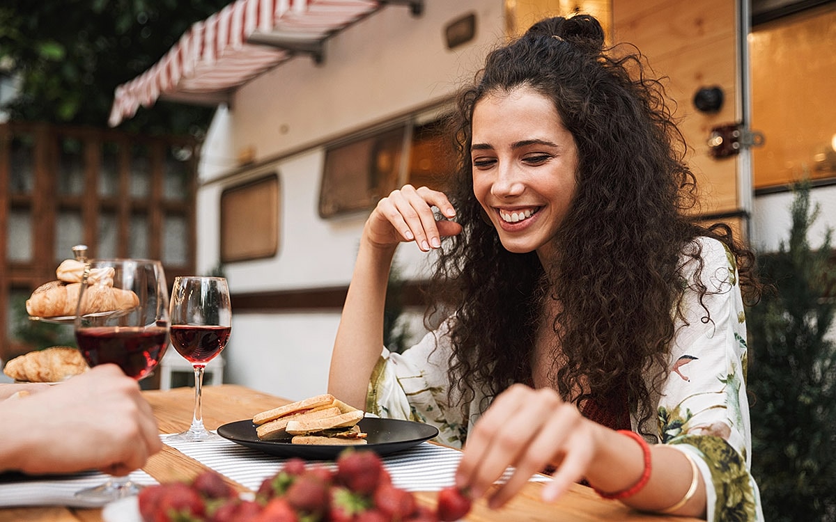 Woman enjoying meal outdoors with wine.