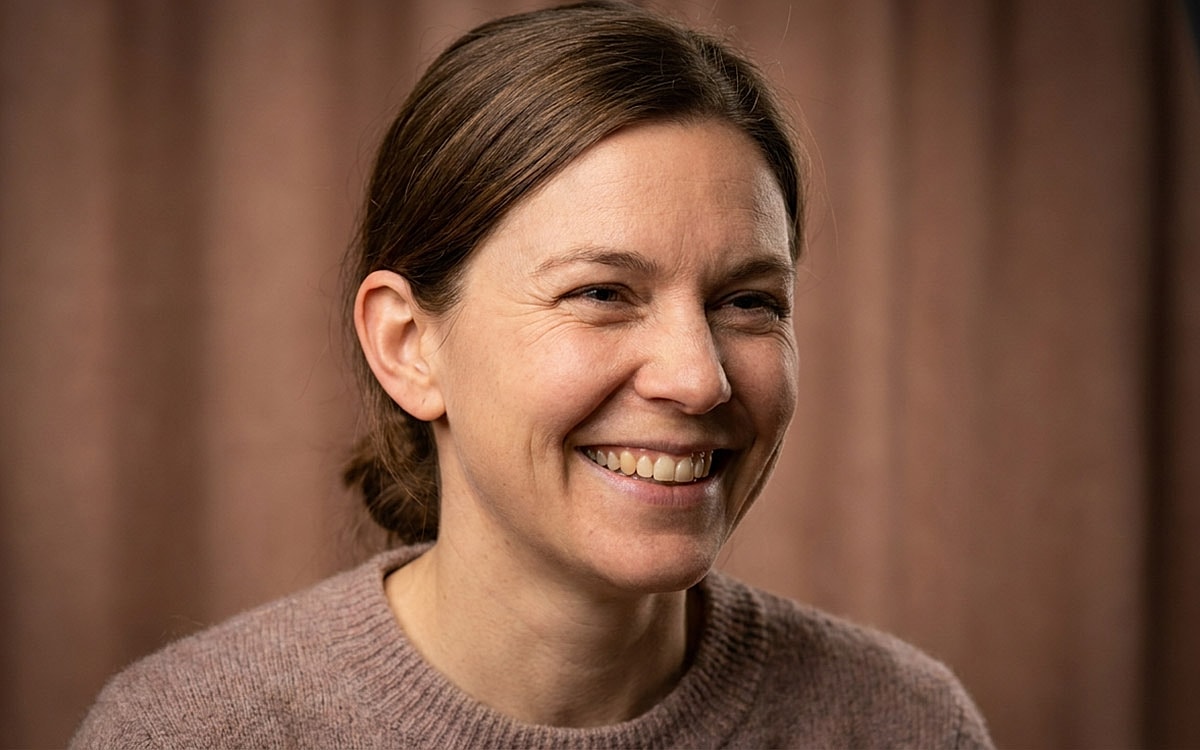 Smiling woman with brown hair in soft sweater.