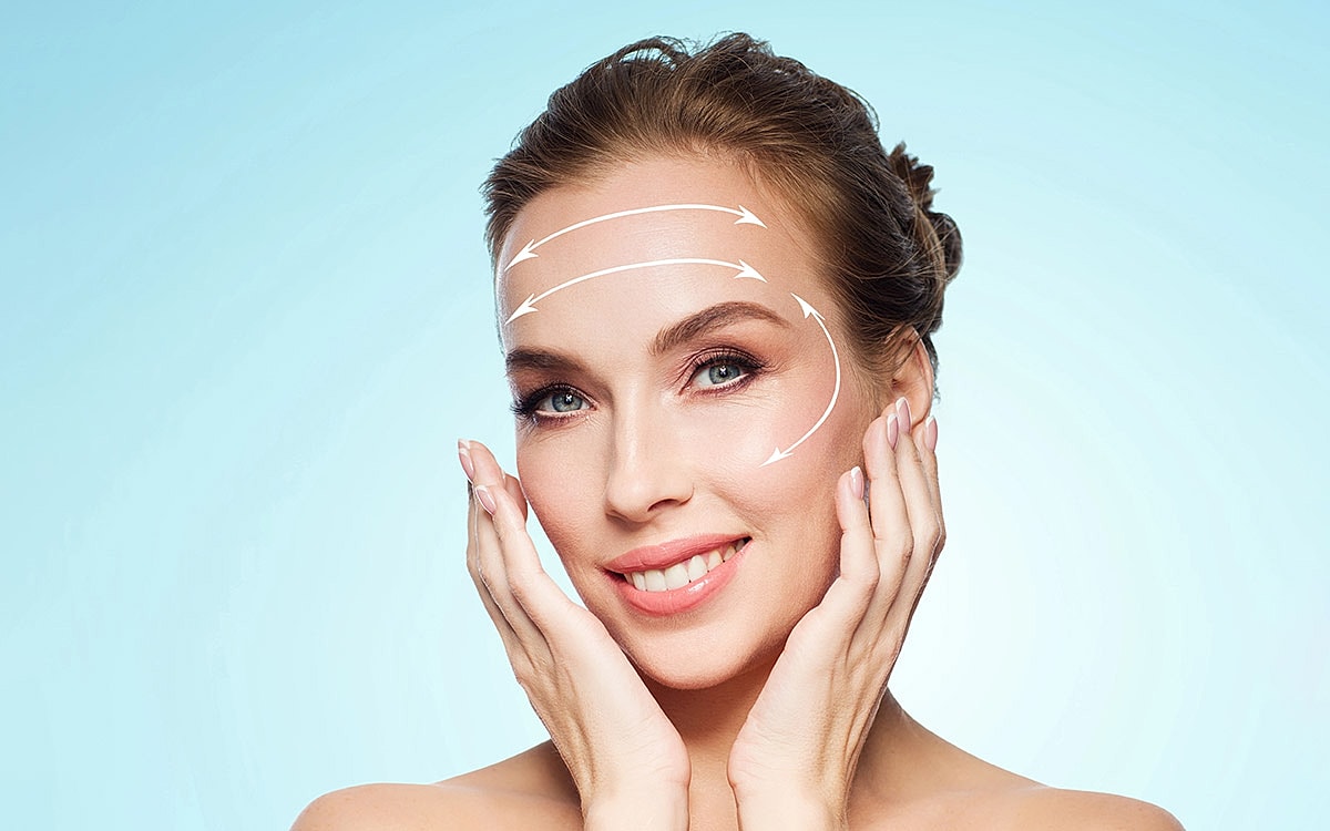 Woman demonstrating facial massage technique on skin.