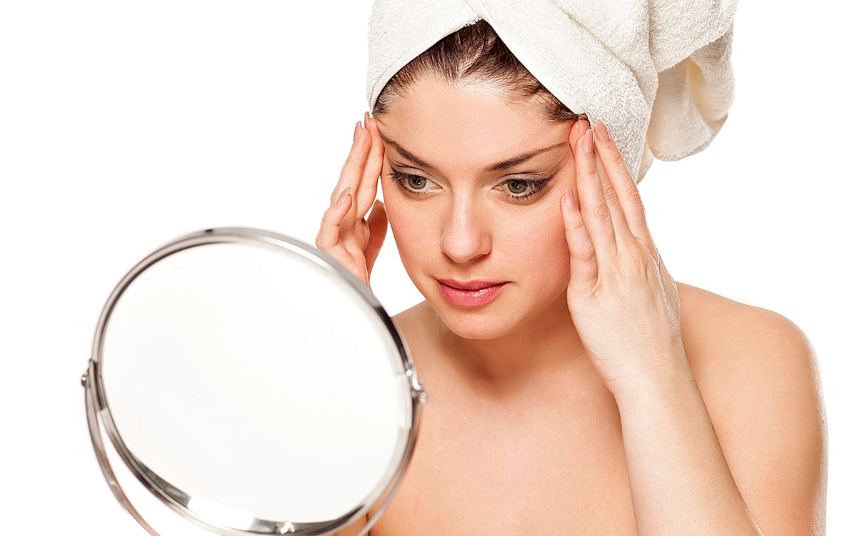 Woman examining skin in mirror after shower.