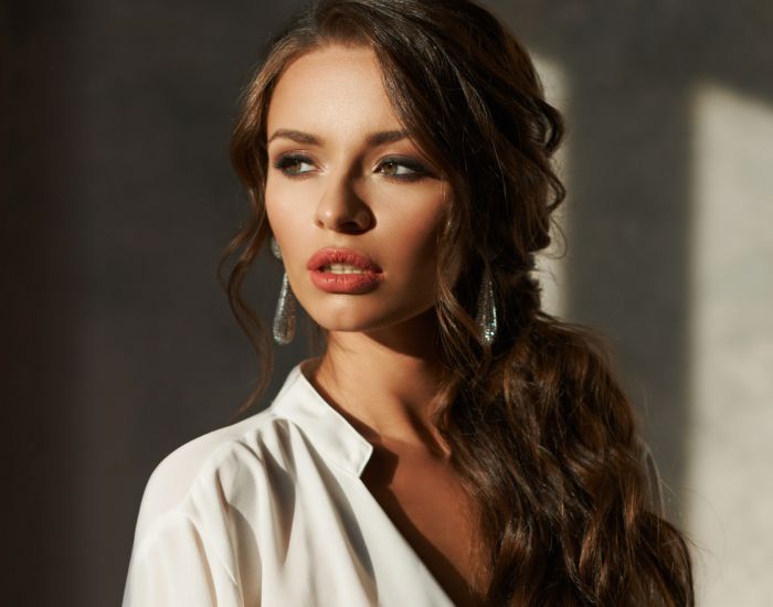Woman with long hair and earrings in sunlight.